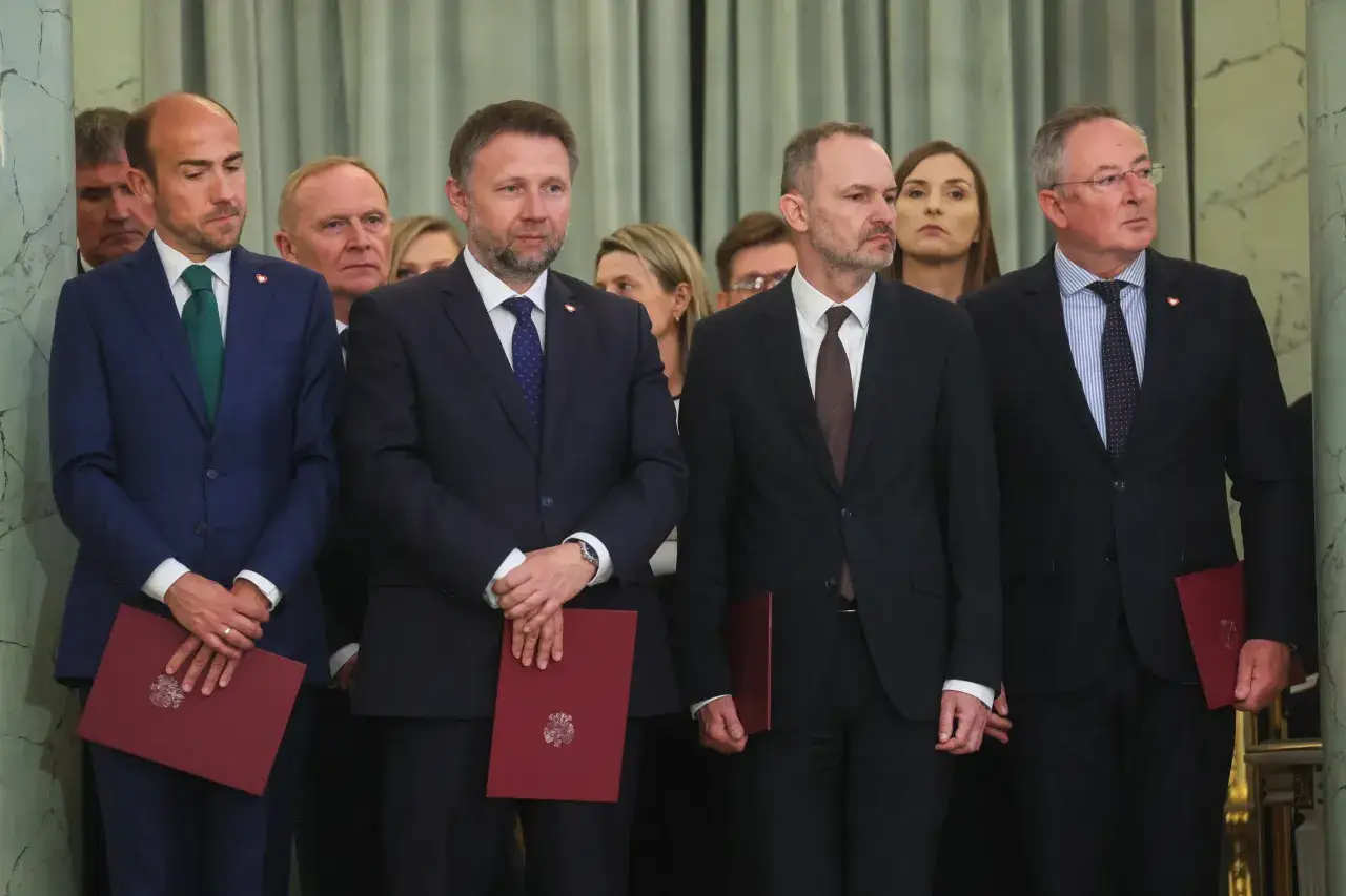 Mężczyźni w garniturach, być może posłowie, stoją w rzędzie, trzymając czerwone dokumenty.