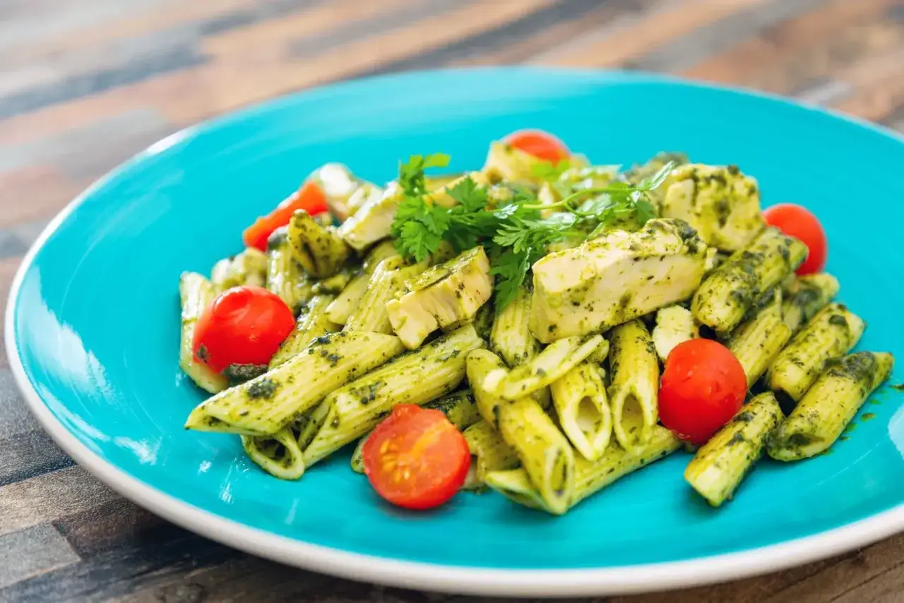 Penne z kurczakiem i pomidorkami koktajlowymi w sosie pesto, z dodatkiem mozzarelli.