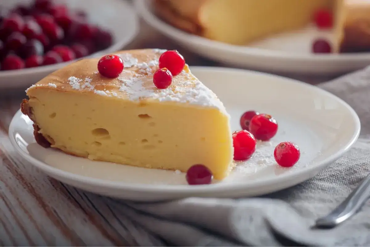 Kawałek puszystego sernika bez budyniu, udekorowany żurawiną i cukrem pudrem. Czy wyjdzie? Wygląda pysznie!