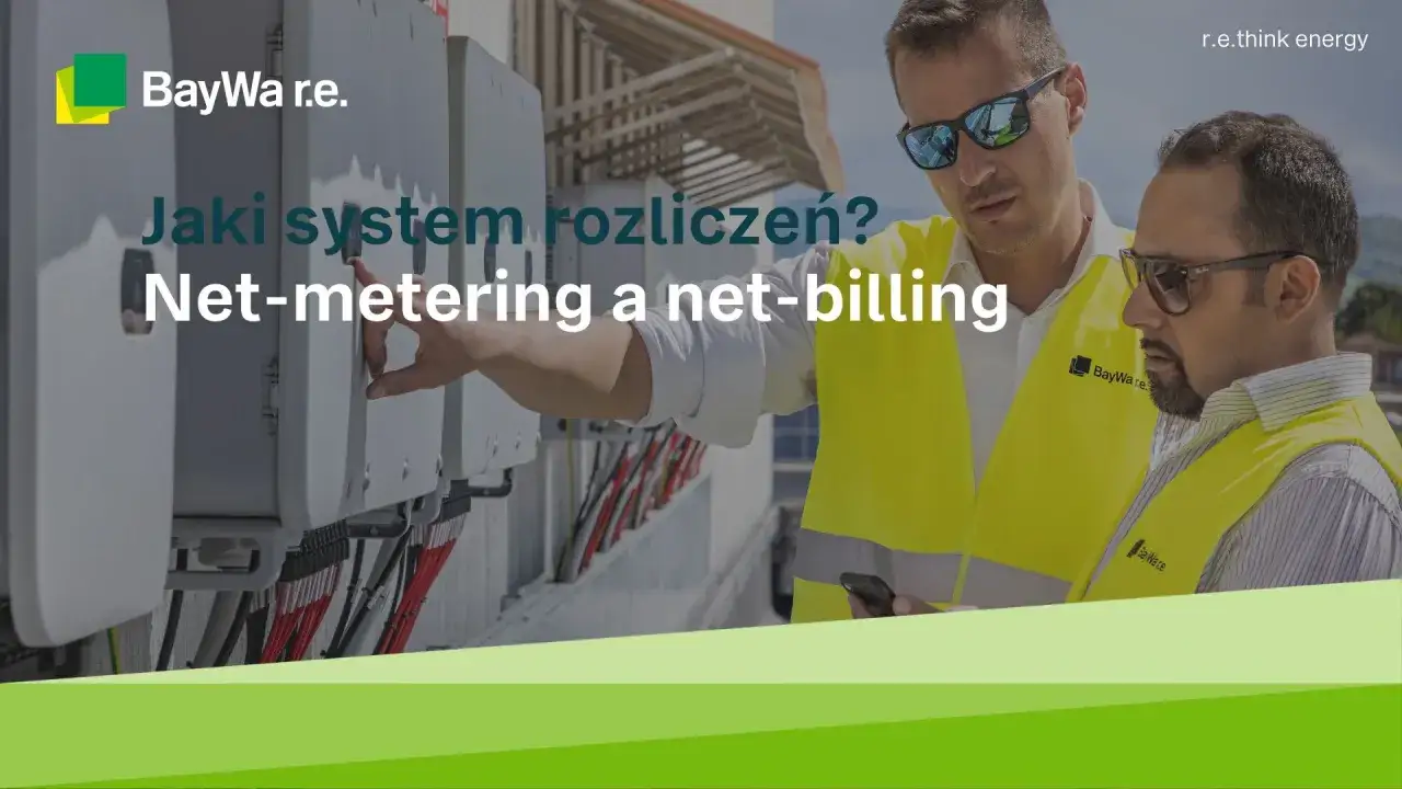 Dwóch mężczyzn w kamizelkach odblaskowych przy panelach, dyskutujących o systemach rozliczeń: net-metering a net-billing.