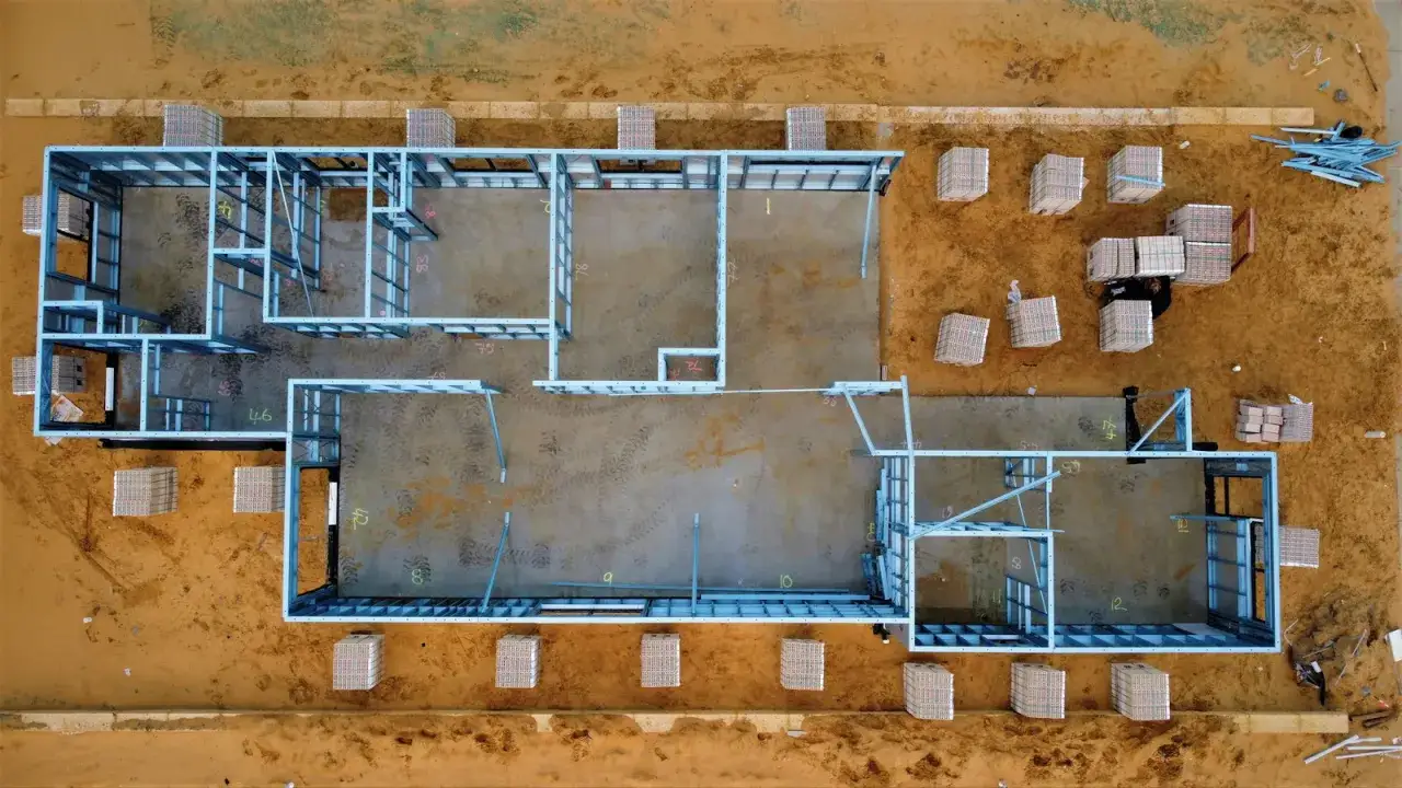 Estructura metálica de una casa en construcción. Se aprecian materiales apilados, listos para el montaje. El precio de hacer un sótano puede variar.