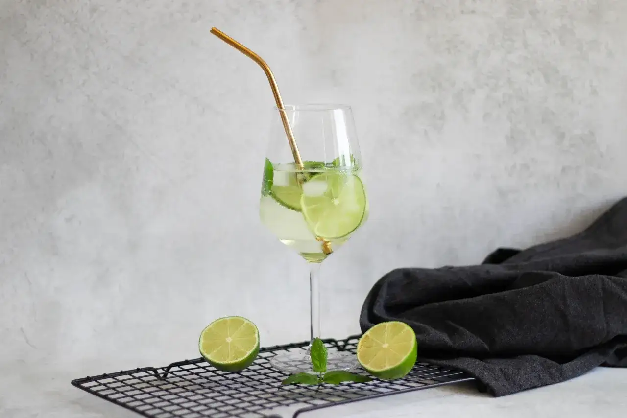 Orzeźwiający drink Hugo z limonką i miętą, idealne proporcje na lato. Złota słomka dodaje elegancji.