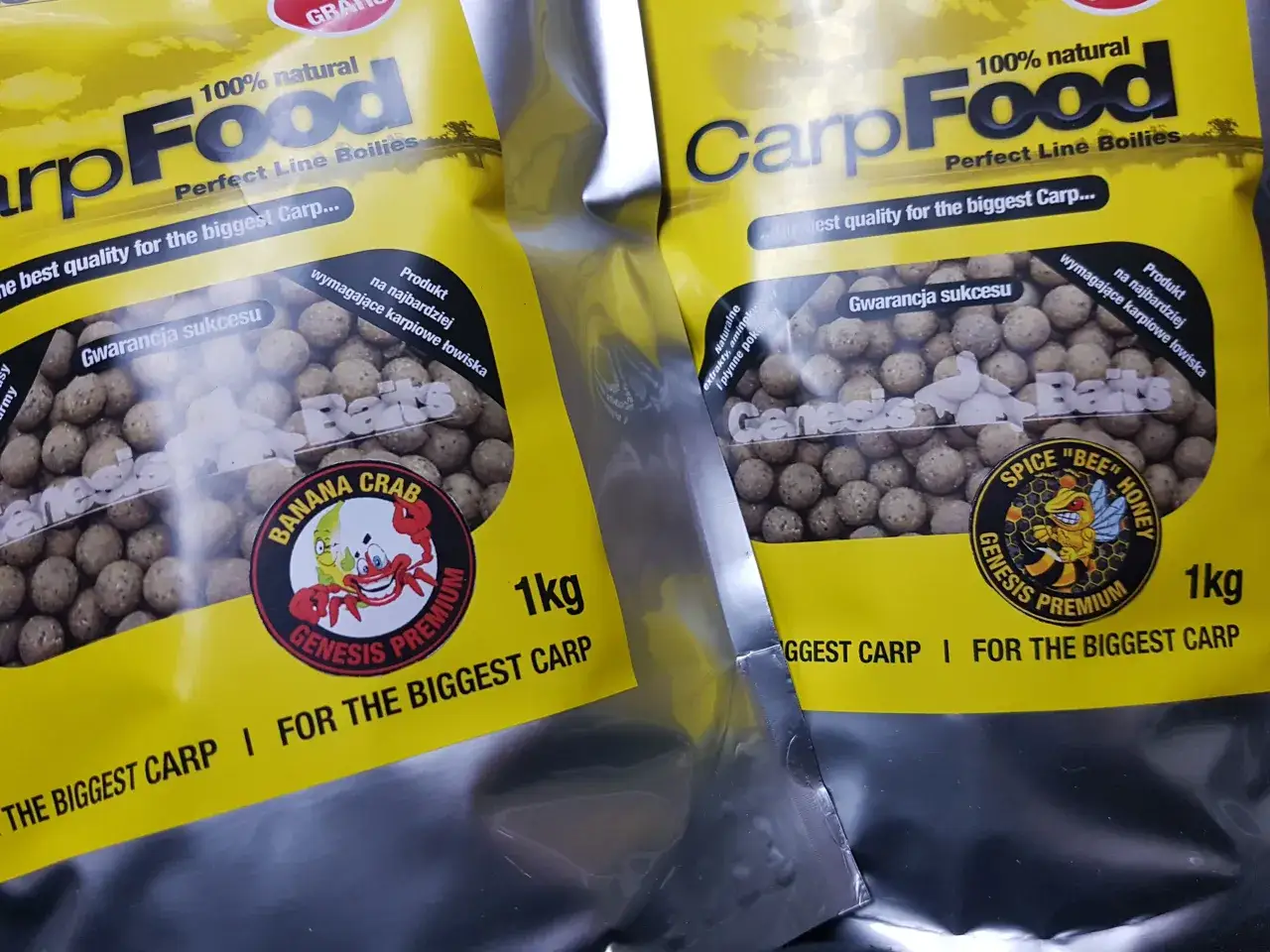 Dwie paczki z żółtymi etykietami zawierają kulki na karpia. Na opakowaniach widnieje napis "CarpFood" i grafika z pszczołą.