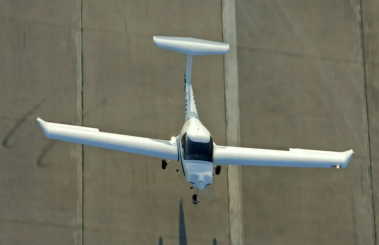 Biały samolot leci nad betonowym pasem.