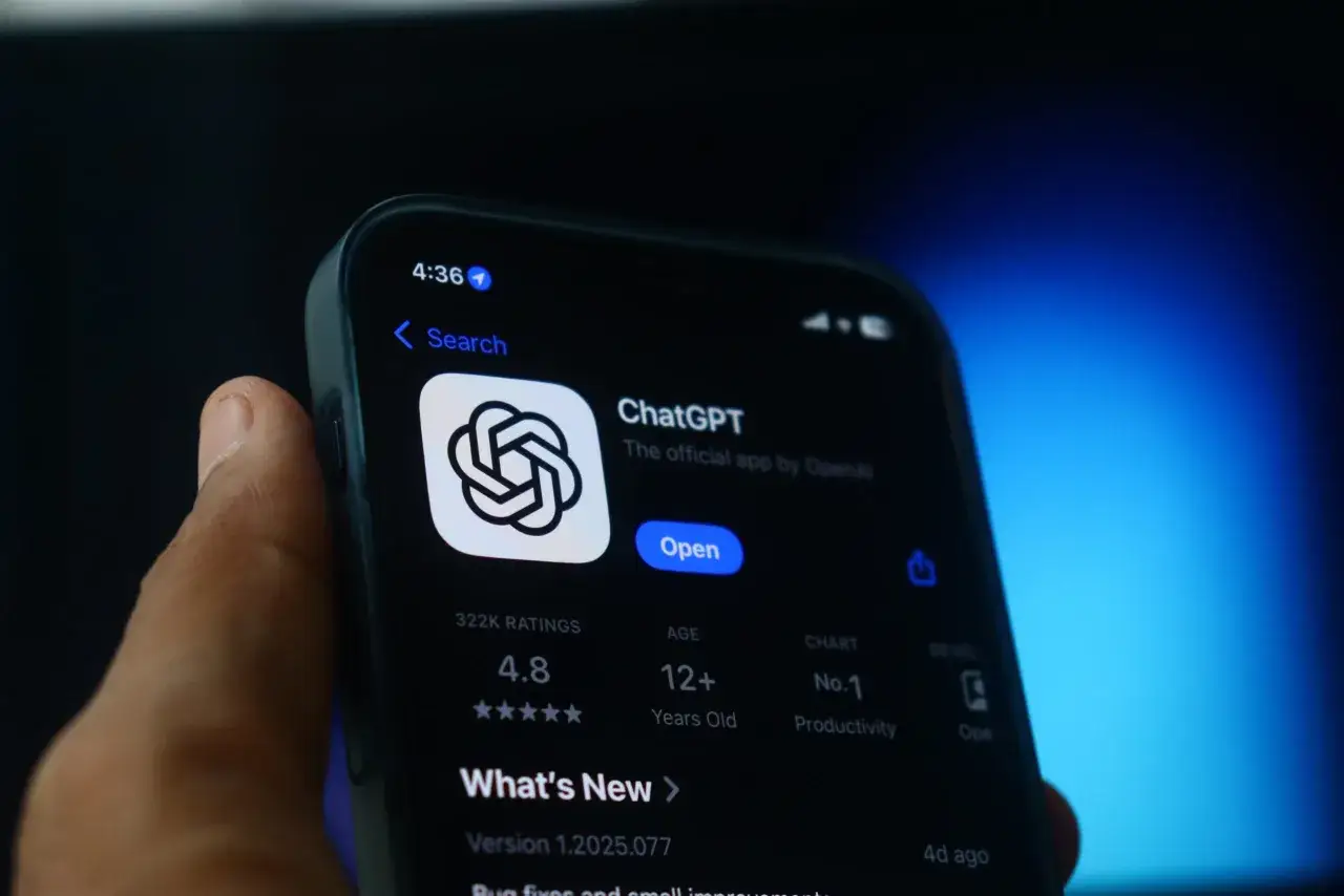 Dłoń trzyma smartfon z ekranem pokazującym aplikację ChatGPT. Zastanawiasz się, jak usunąć AI z telefonu?