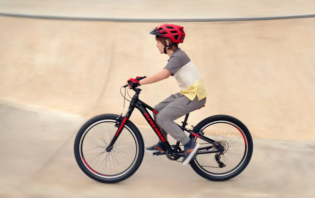Chłopiec w kasku pędzi na rowerze po betonowym torze.