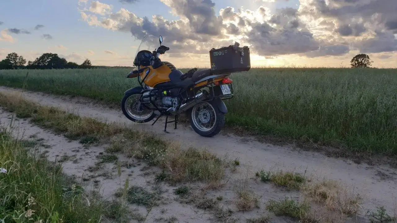 Żółty motocykl turystyczny na piaszczystej drodze wśród pól. Idealne miejsce na odkrywanie tras motocyklowych Kaszuby.