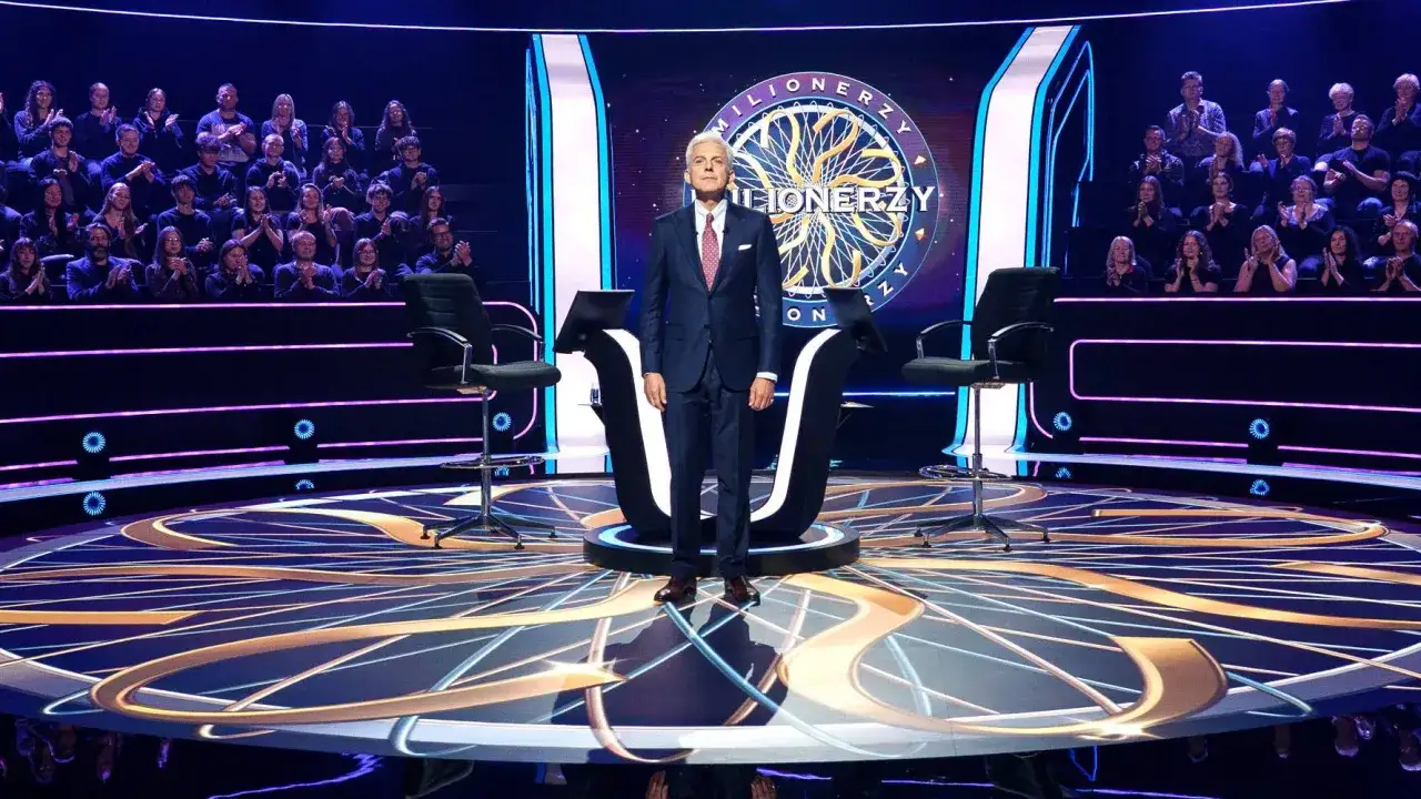 Na scenie "Milionerów" stoi prowadzący. Widownia siedzi w tle. Pytanie brzmi: jakie są koła ratunkowe w Milionerach?