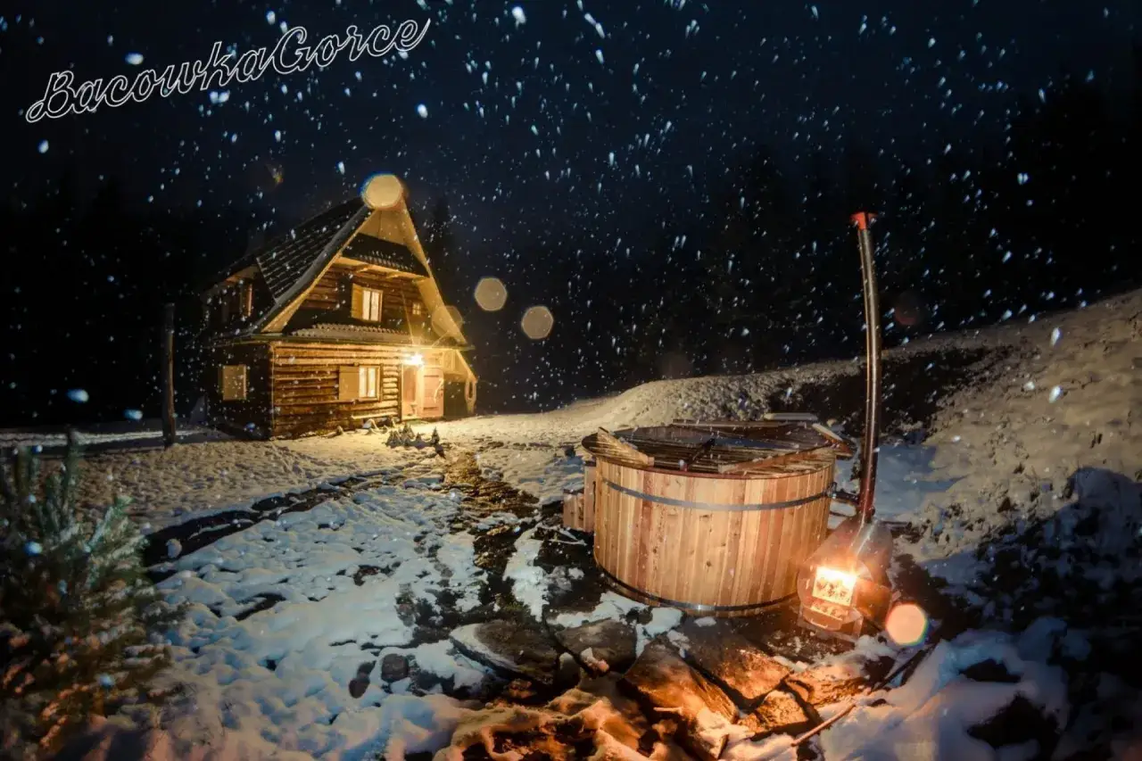Nocą w bacówce u Winiarskich, przytulny drewniany domek i gorąca balia w śnieżnej scenerii.