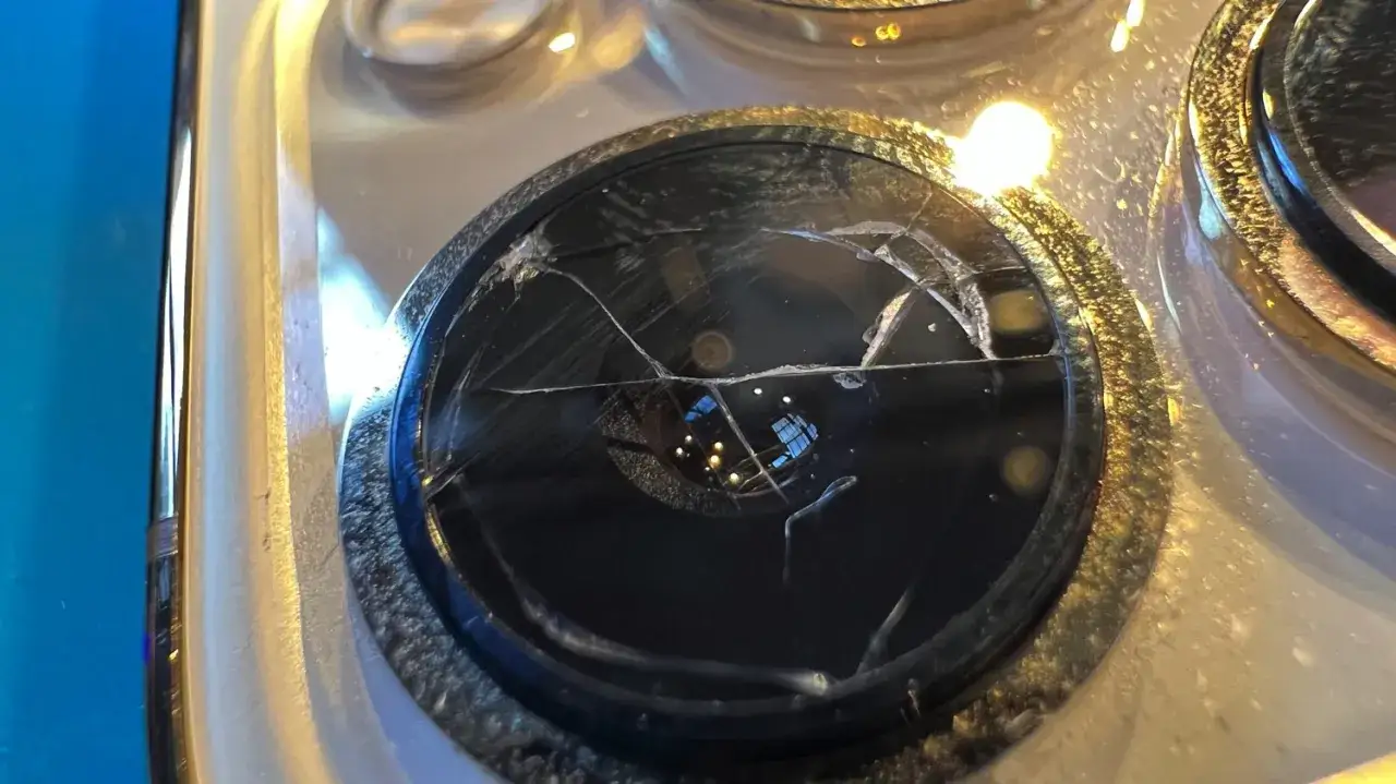 Pęknięte szkiełko obiektywu aparatu telefonu komórkowego.