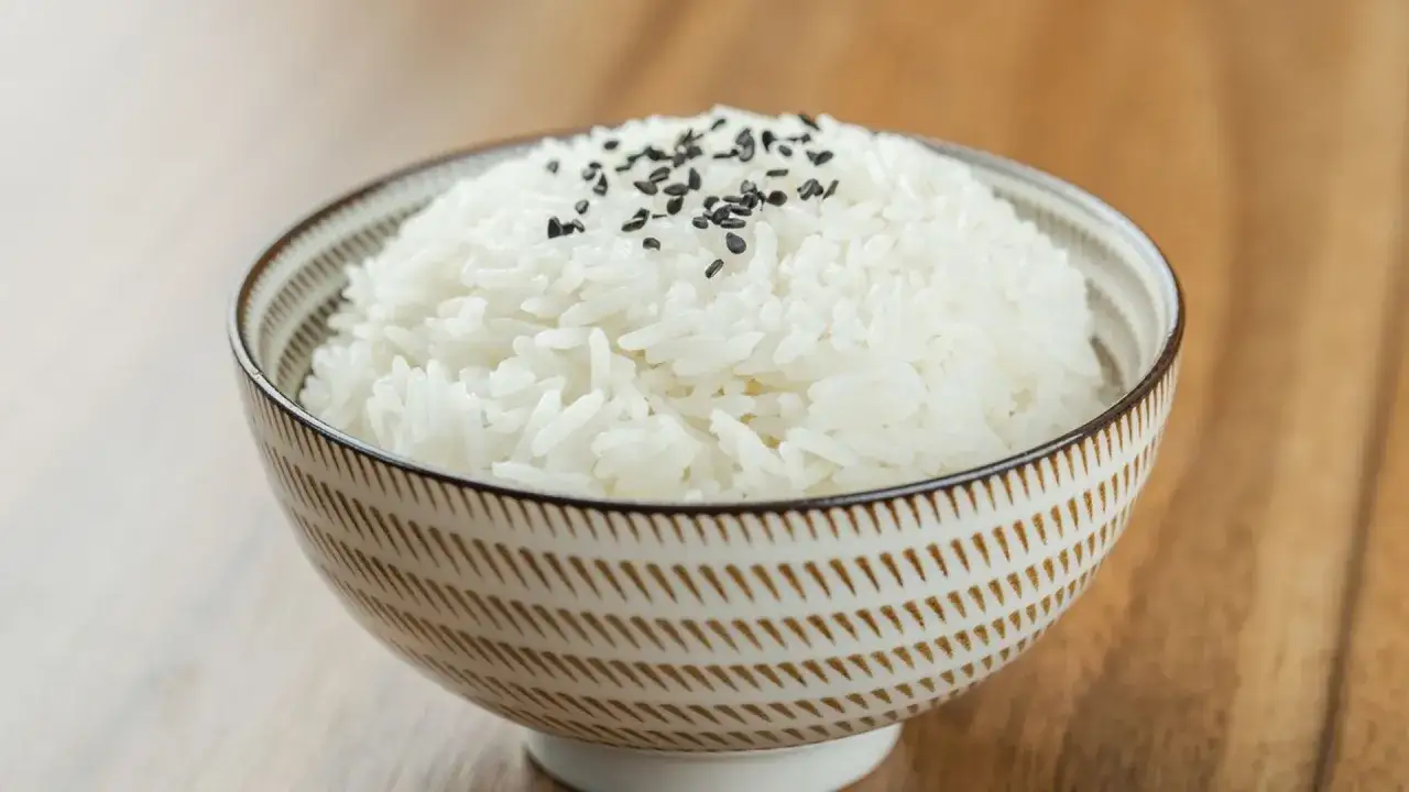 Miseczka puszystego ryżu basmati, posypana czarnym sezamem. Idealny przykład, jak ugotować ryż basmati.