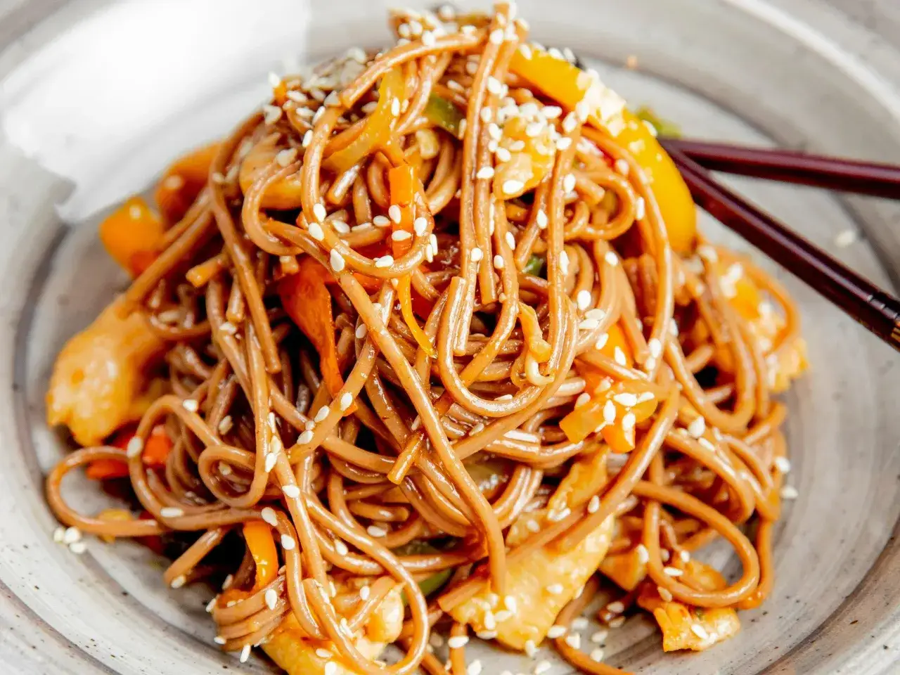 Soba z kurczakiem i warzywami, posypana sezamem. Pyszny przepis na soba, idealny na szybki obiad.