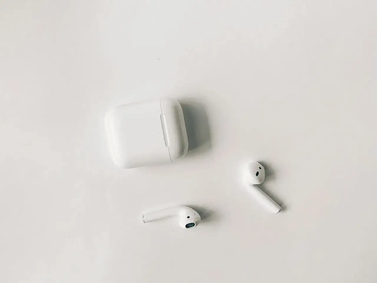 Białe słuchawki AirPods i etui na białym tle. Czy airpods działają z androidem? Tak, można je sparować.