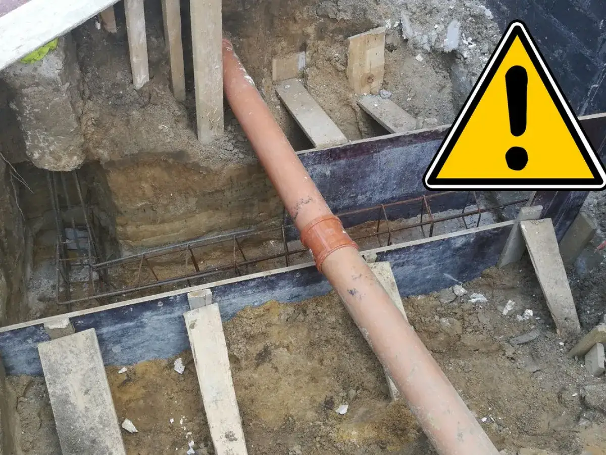 Budowa domu: widoczna rura kanalizacyjna w wykopie, zbrojenie i elementy szalunku.