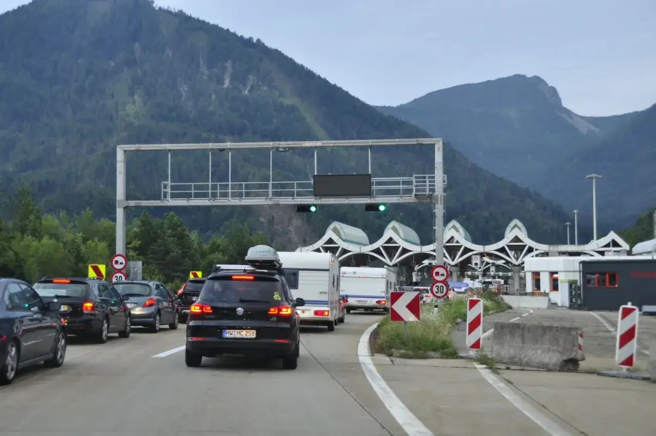 Korki na autostradzie przed punktem poboru opłat z widokiem na góry.