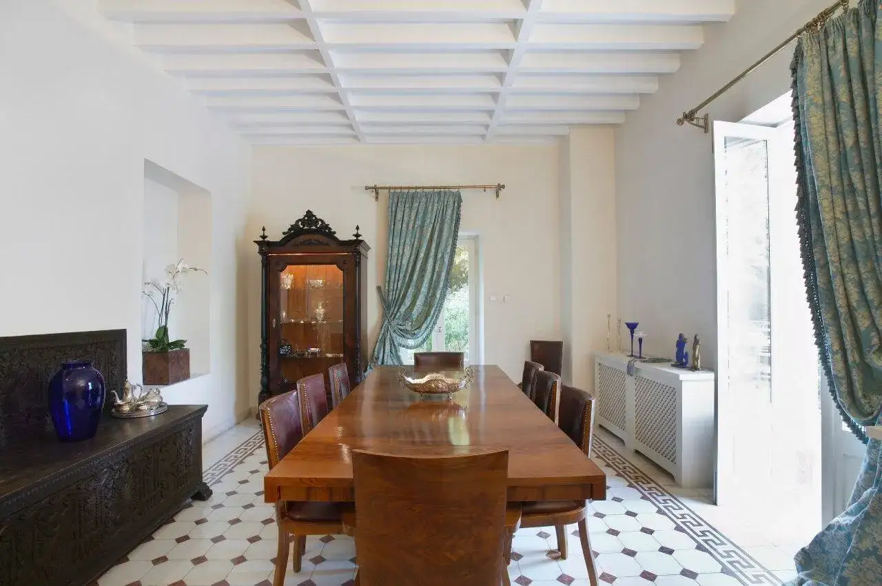 Elegancki salon w stylu kolonialnym z drewnianym stołem, witryną i zdobioną skrzynią.