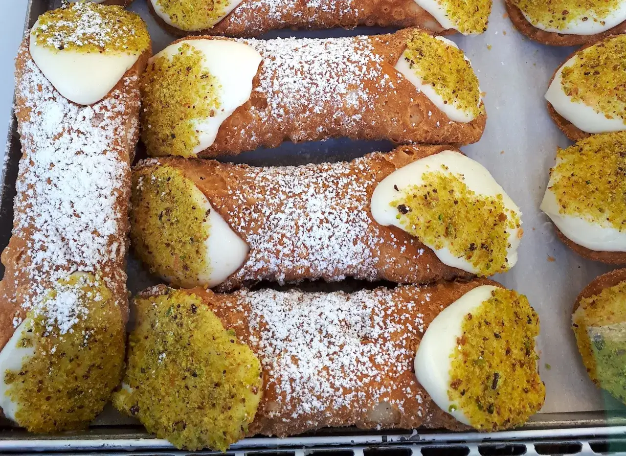 Chrupiące rurki z kremem i pistacjami, posypane cukrem pudrem. Idealny przepis na Cannoli.