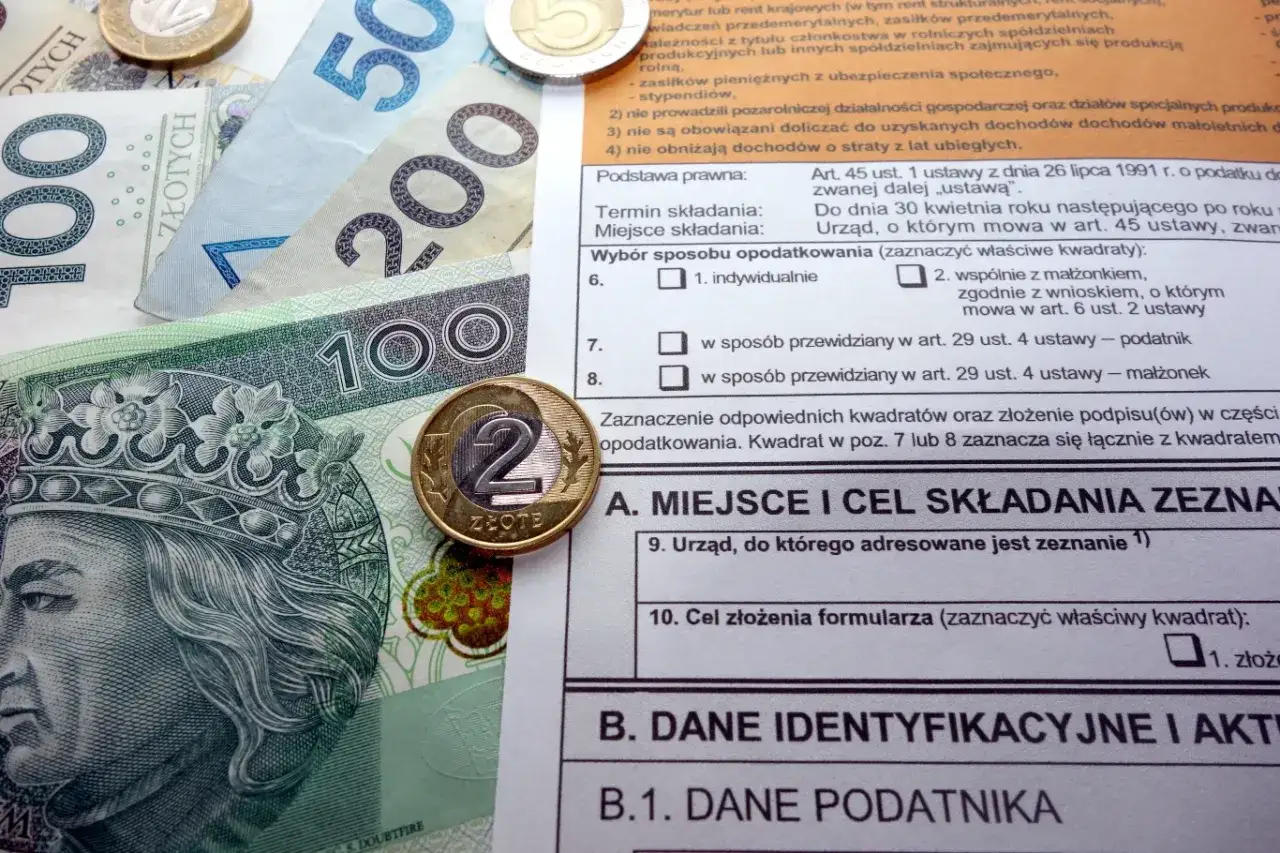 Polskie banknoty i monety na tle formularza podatkowego, ilustrujące ulga termomodernizacyjna – przykład rozliczenia.