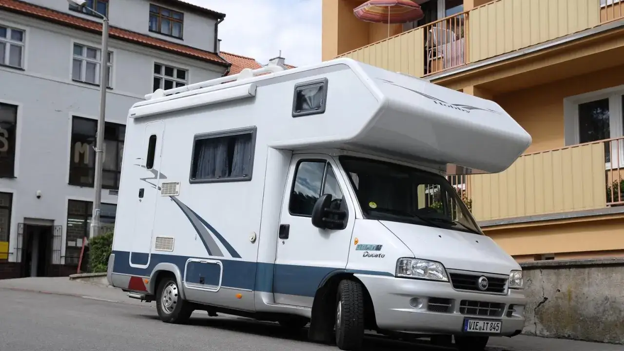 Biały kamper Fiat Ducato zaparkowany na ulicy. Zastanawiasz się, ile miejsc ma bus tego typu?