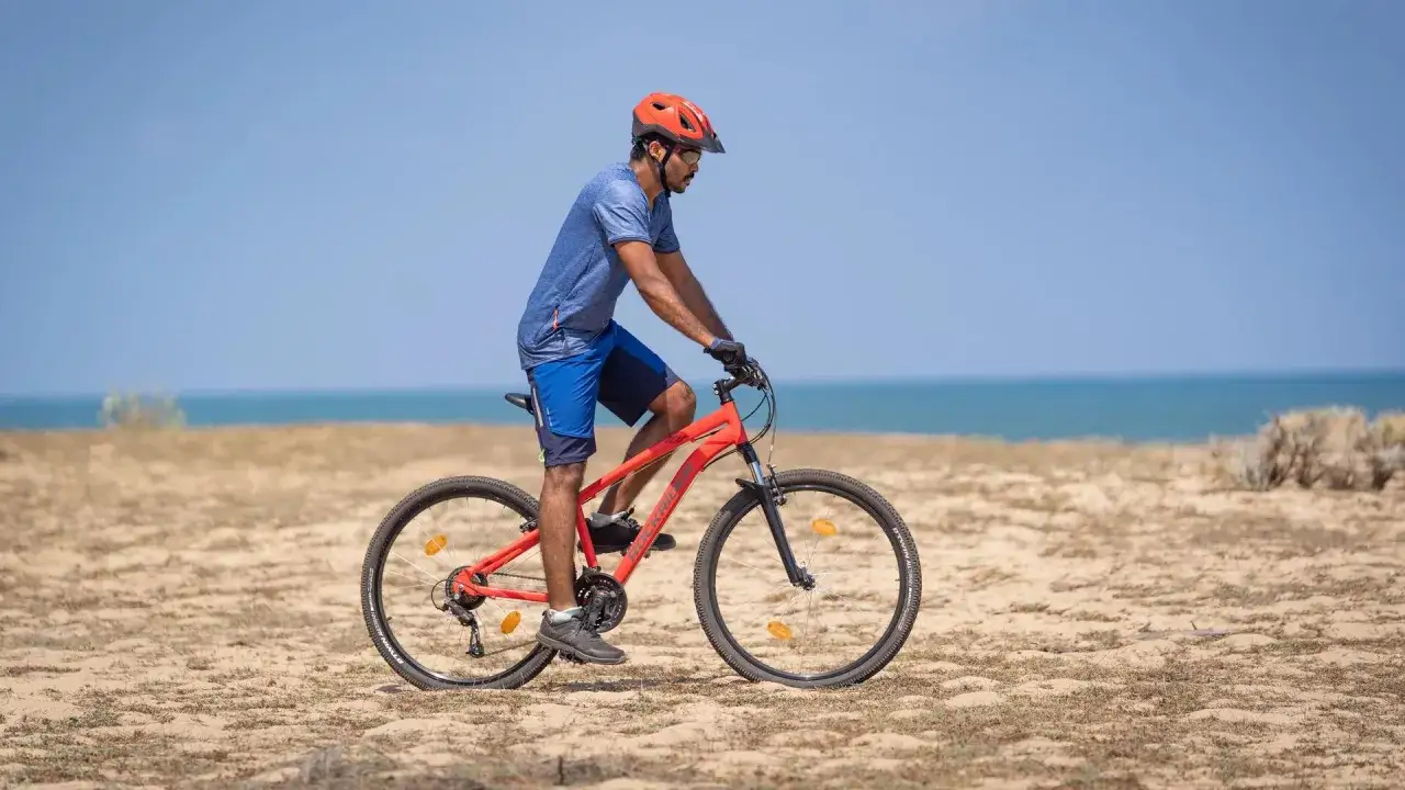 Mężczyzna w kasku jedzie na rowerze po plaży. Sprawdź, co obejmuje gwarancja roweru, by mieć pewność podczas każdej wyprawy.