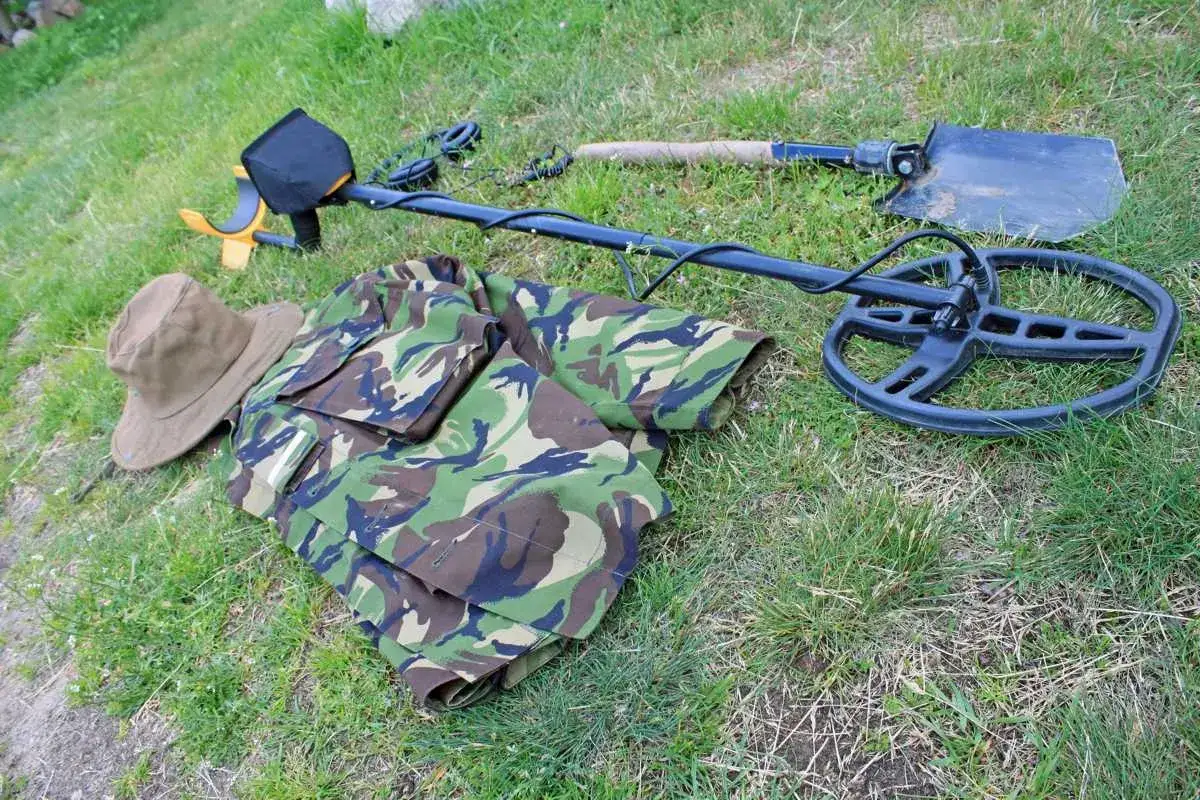 Wykrywacz metali, łopata, mundur i kapelusz na trawie.