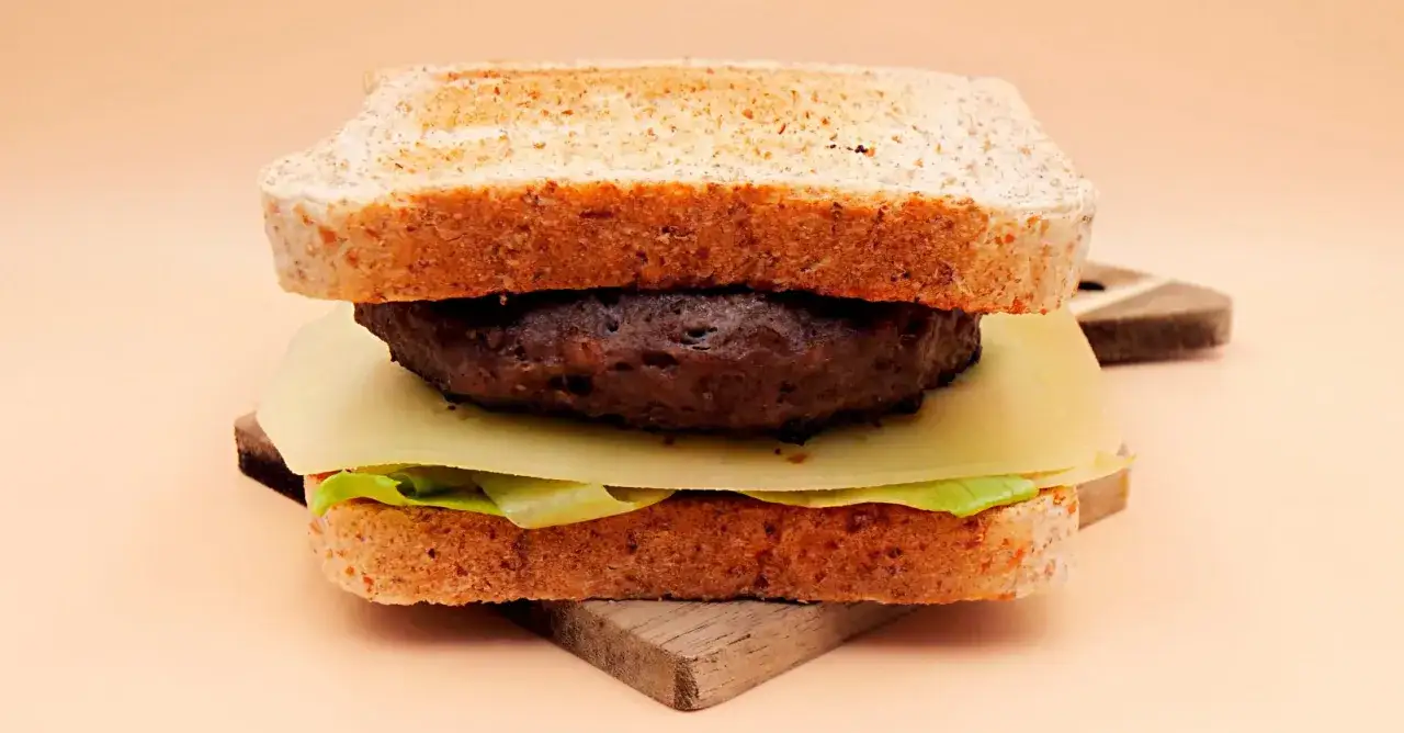 Burger z wołowiny, serem, sałatą i tostami na desce.