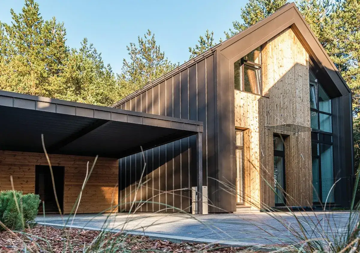 Nowoczesna stodoła elewacja z drewna i ciemnego metalu, zadaszenie nad wejściem i carportem, otoczona drzewami.