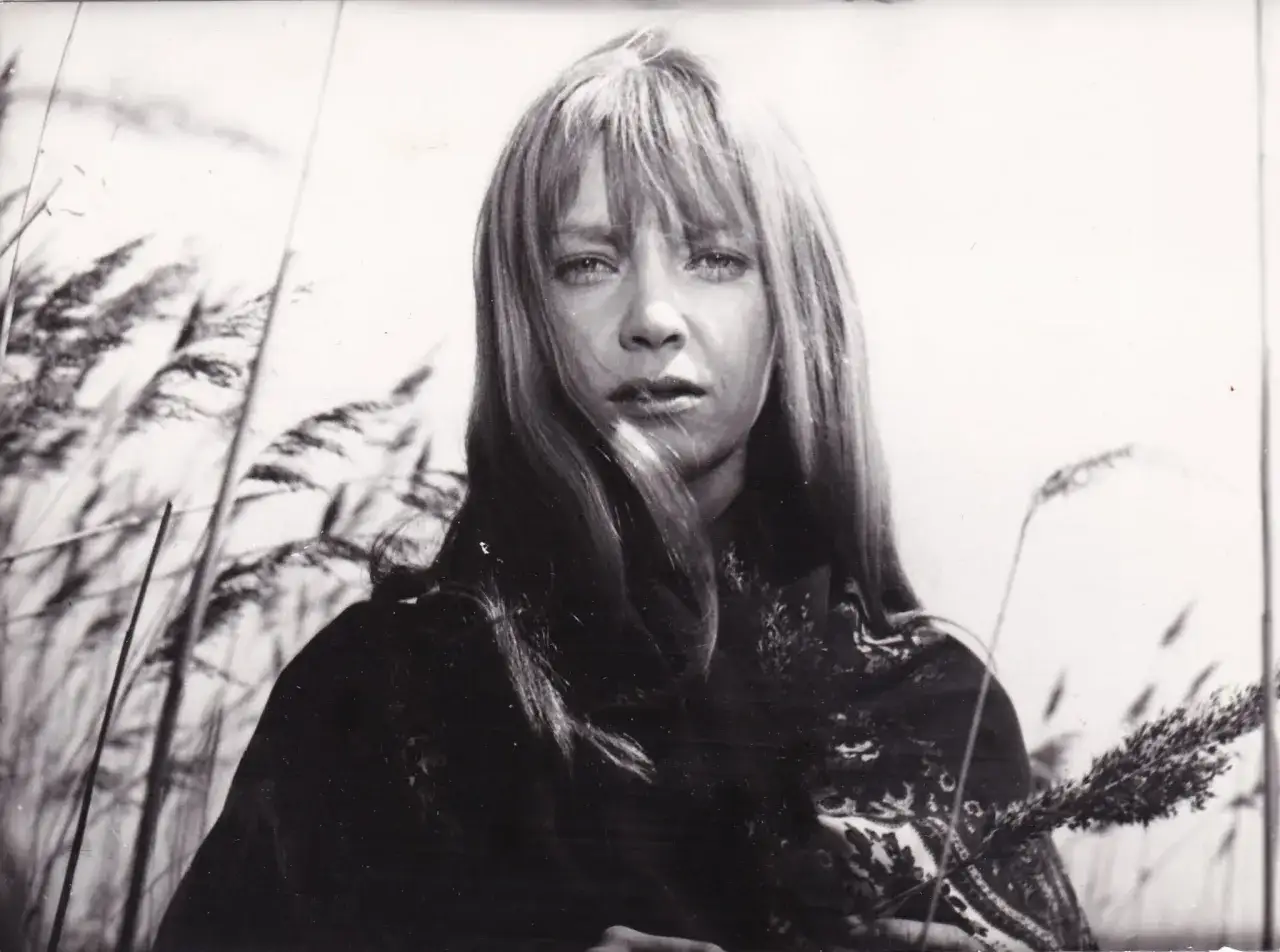 Irena Szczurowska w otoczeniu trzcin, zamyślona, z kosmykami włosów opadającymi na twarz.