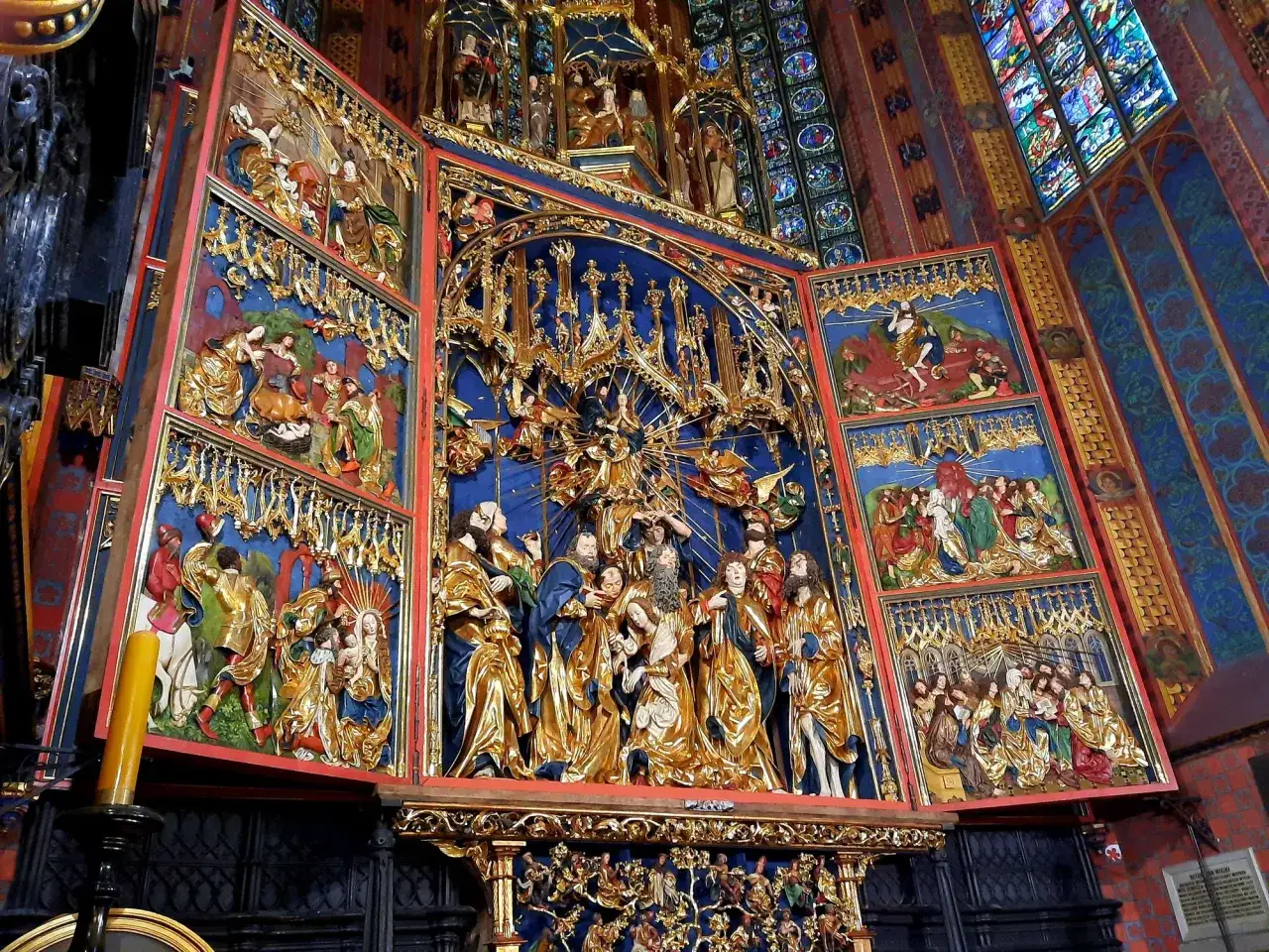 Ołtarz Wita Stwosza: złote rzeźby postaci biblijnych na niebieskim tle, w kościele.