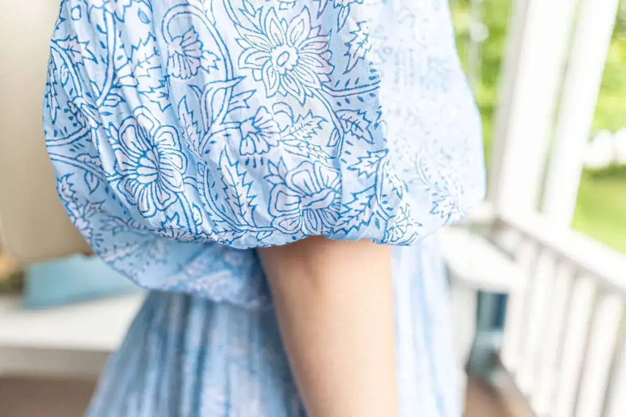 Biała sukienka w niebieskie kwiaty, zbliżenie na rękaw.