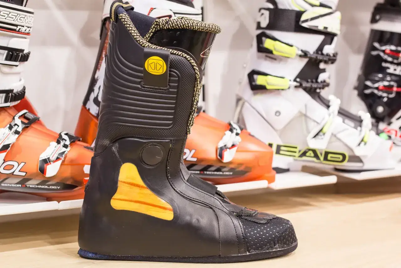 Czarne buty narciarskie podgrzewane z pomarańczowymi akcentami, gotowe na zimowe szaleństwo.