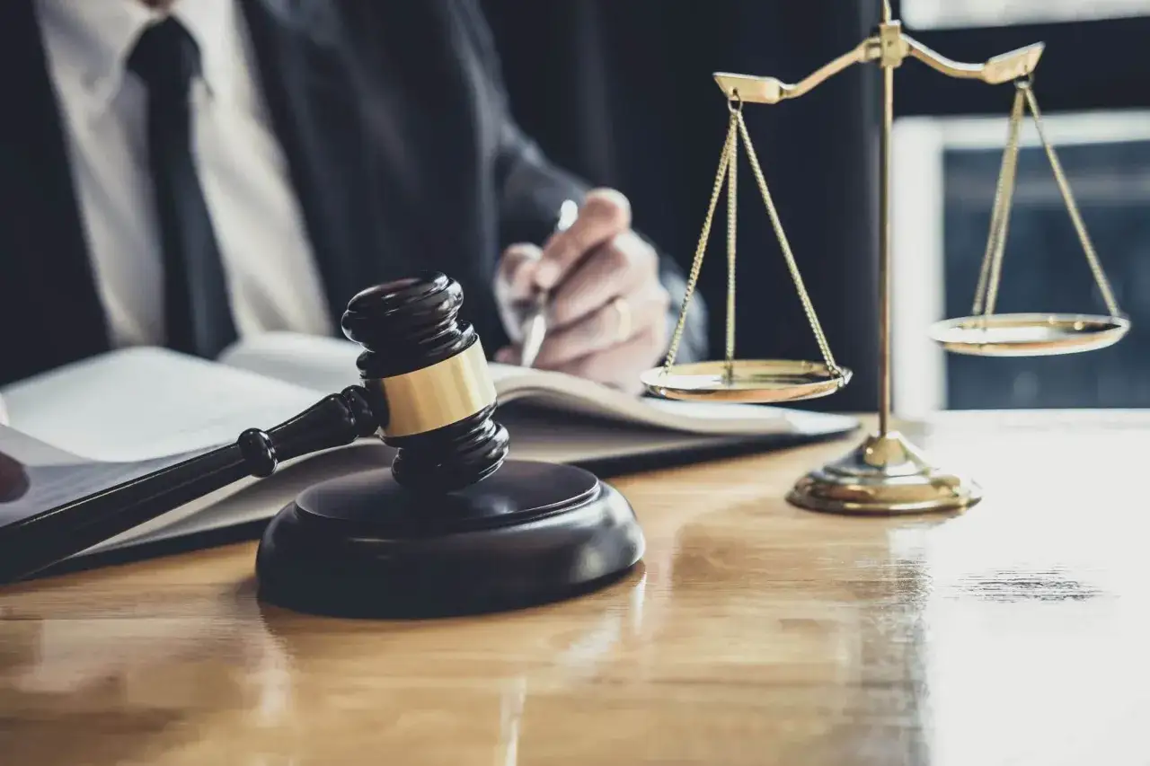 Sądowy młotek i waga sprawiedliwości na biurku. Prawnik pisze, zastanawiając się, po ilu latach przedawnia się prawo do spadku.