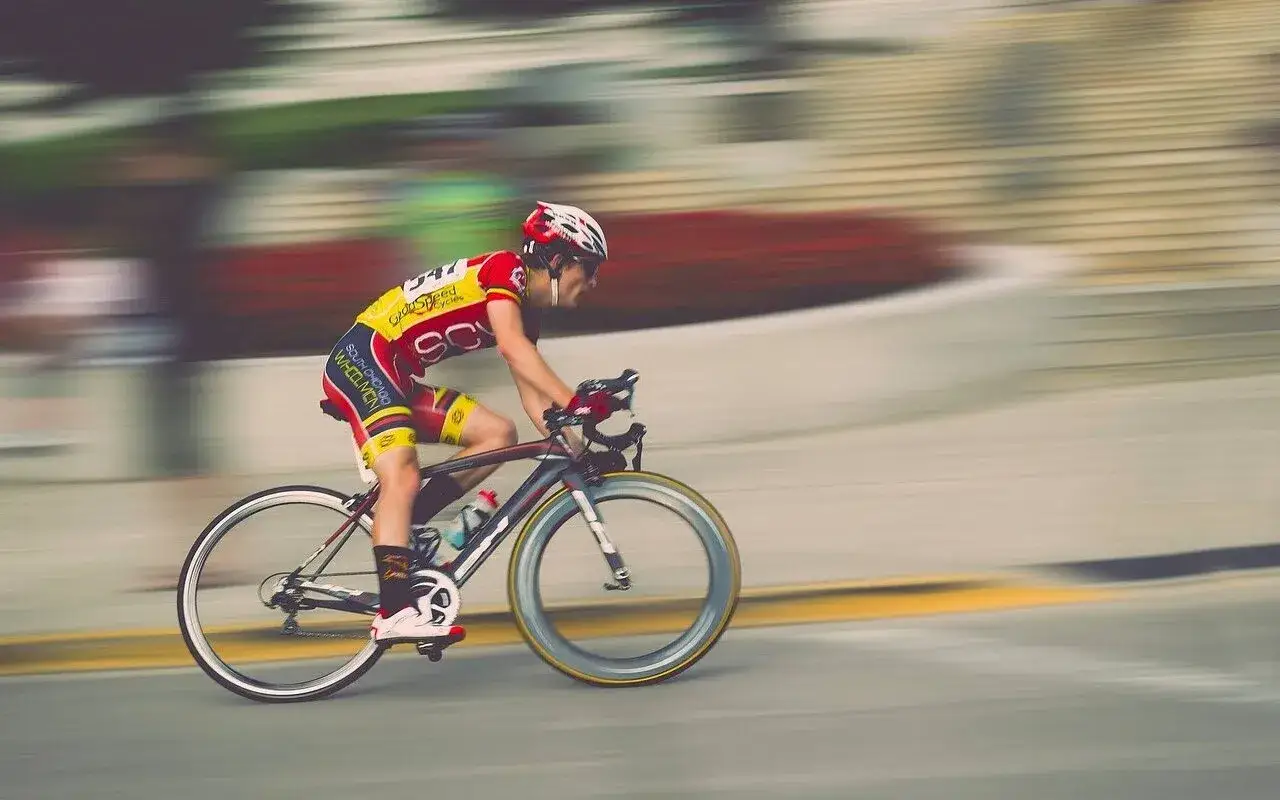 Kolarz w żółto-czerwonym stroju pędzi na rowerze podczas maratonu rowerowego.