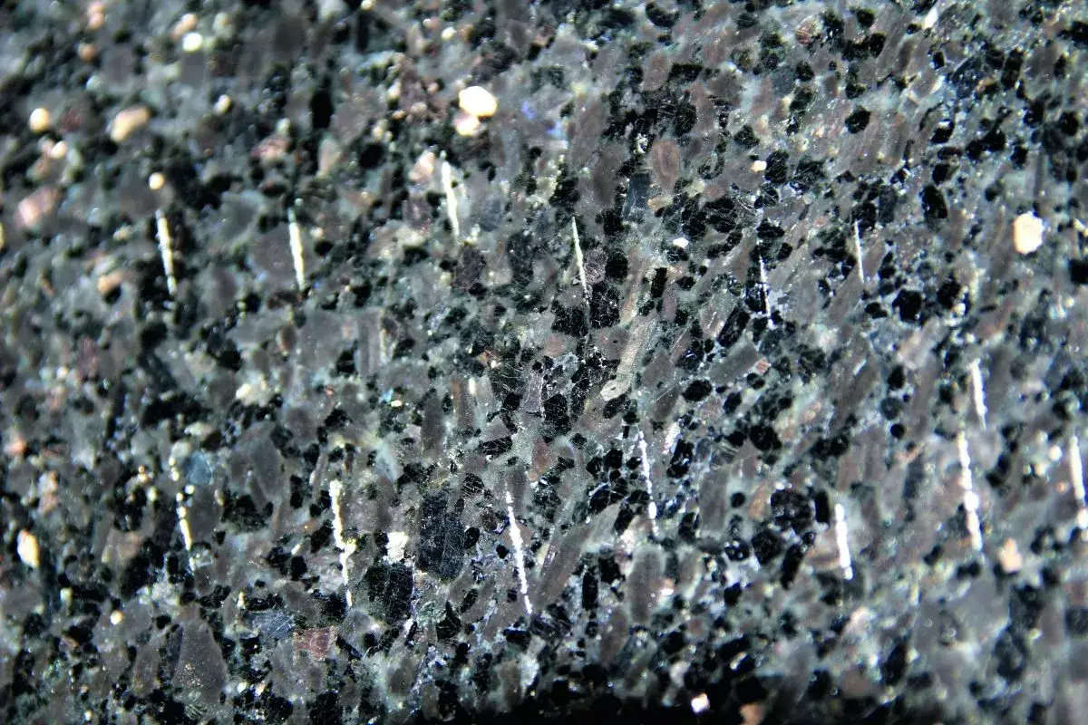 Zbliżenie na ciemny, granitowy blat kuchenny z widocznymi białymi, pionowymi rysami.