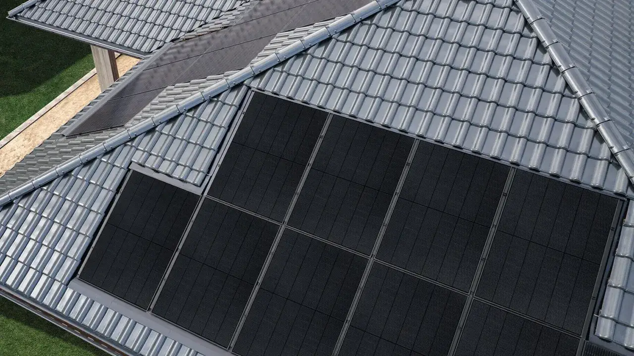 Dach z szarymi dachówkami i panelami fotowoltaicznymi.