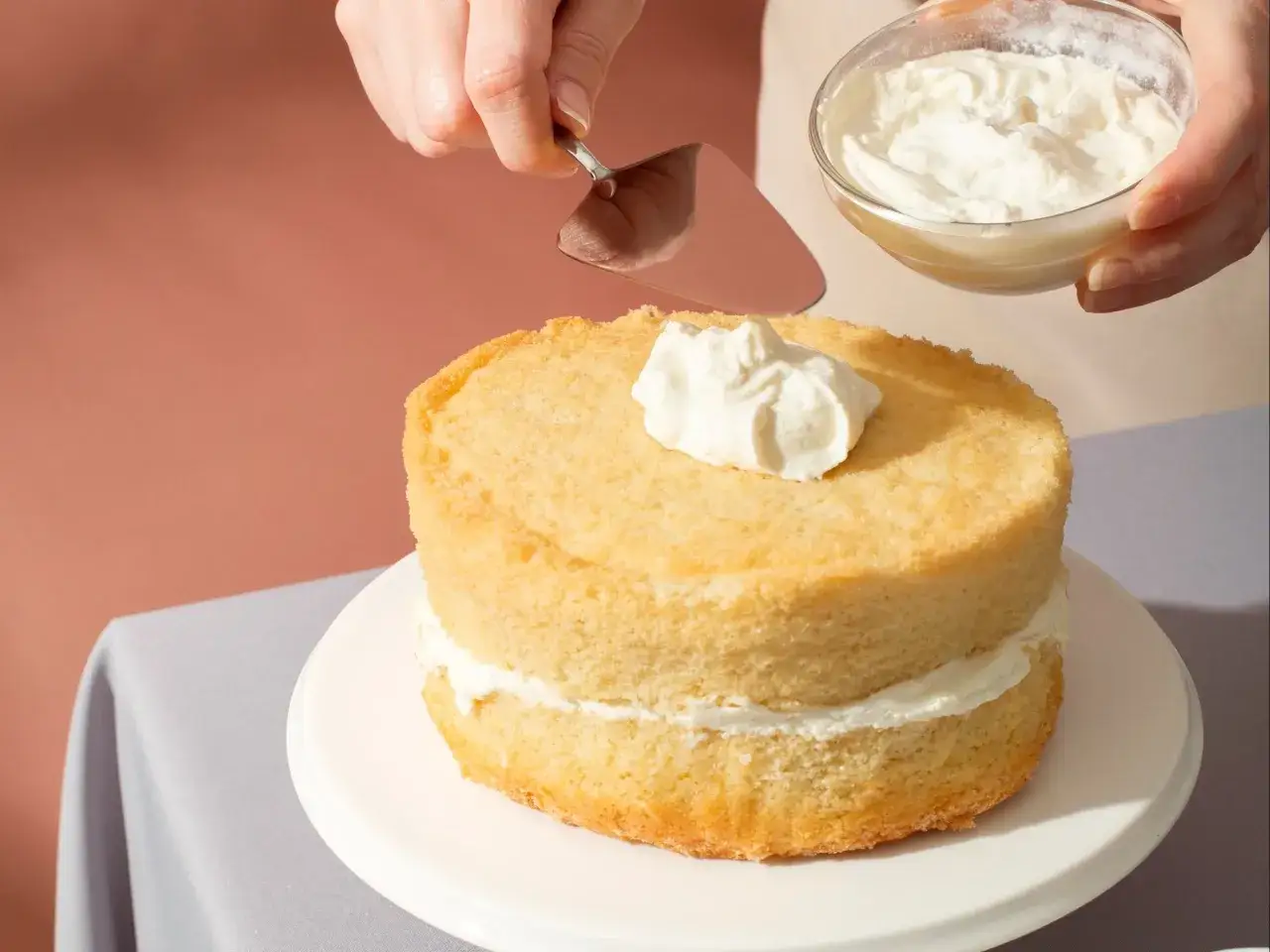 Nakładanie puszystego kremu na biszkoptowe ciasto z mascarpone.