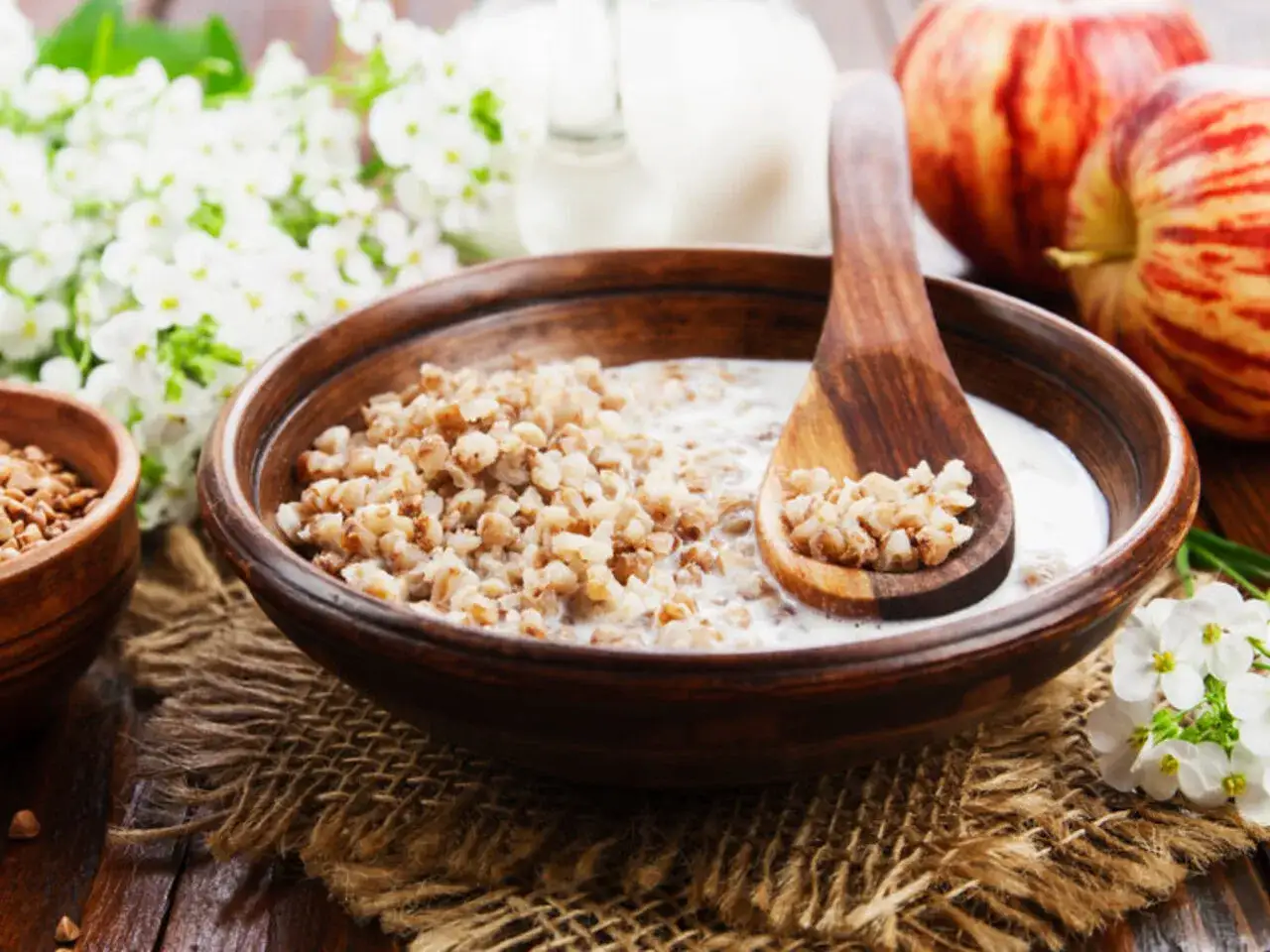 Zdrowy posiłek: kasza gryczana z mlekiem, jabłka i kwiaty. Idealny przykładowy jadłospis przy miażdżycy.