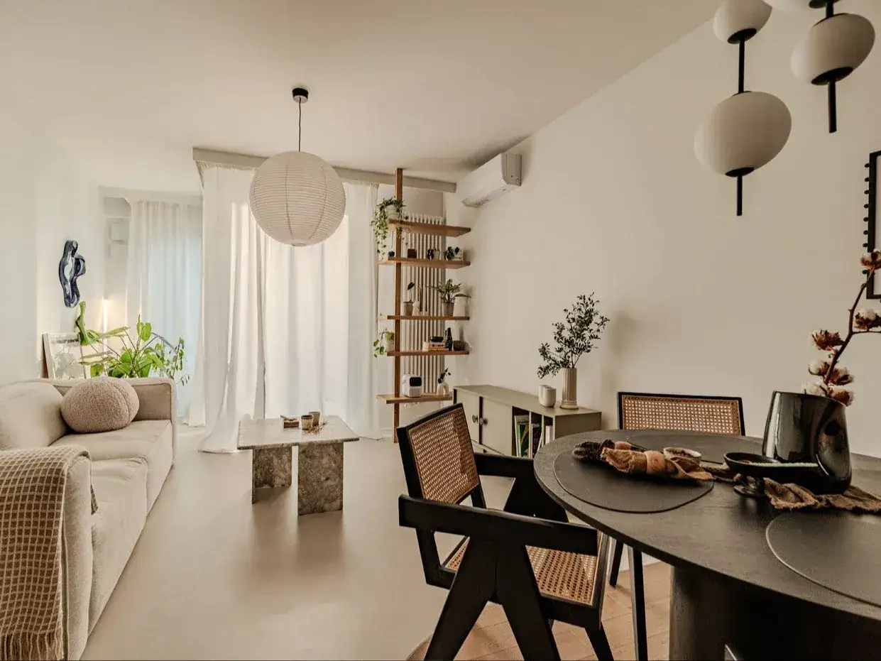 Salon w stylu japandi z beżową sofą, kamiennym stolikiem i drewnianymi meblami.