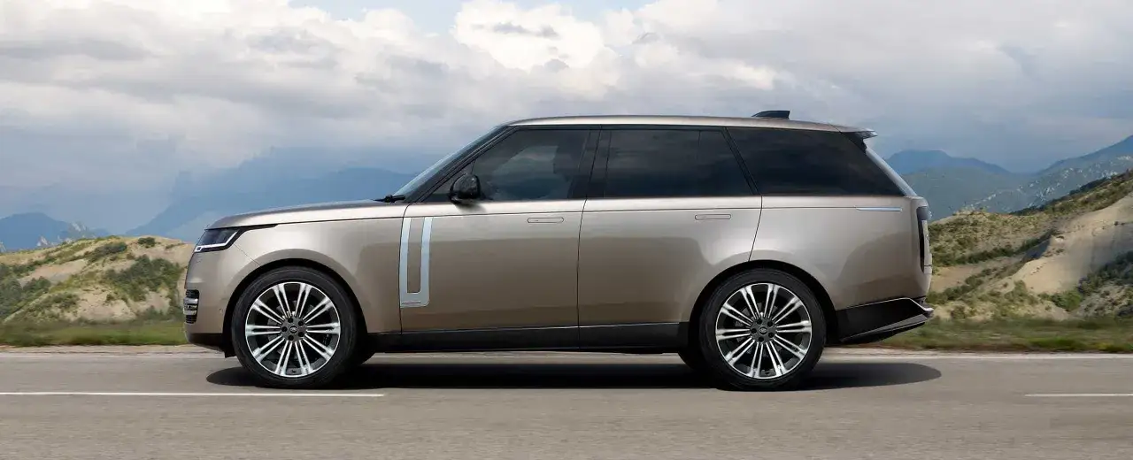 Brązowy SUV Range Rover na tle górskiego krajobrazu.