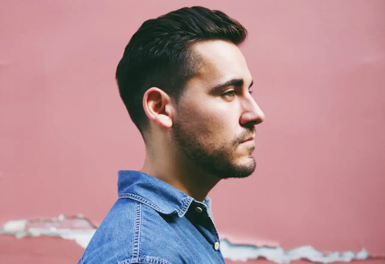 Mężczyzna w dżinsowej koszuli, zamyślony, zmagający się z niestabilnością emocjonalną u mężczyzn.