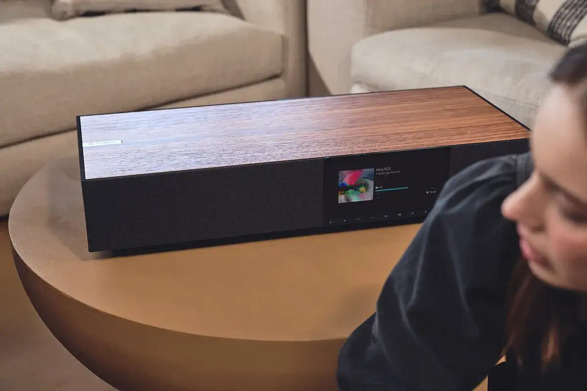 Elegancki Cambridge Audio One z drewnianym blatem i ekranem odtwarza muzykę.