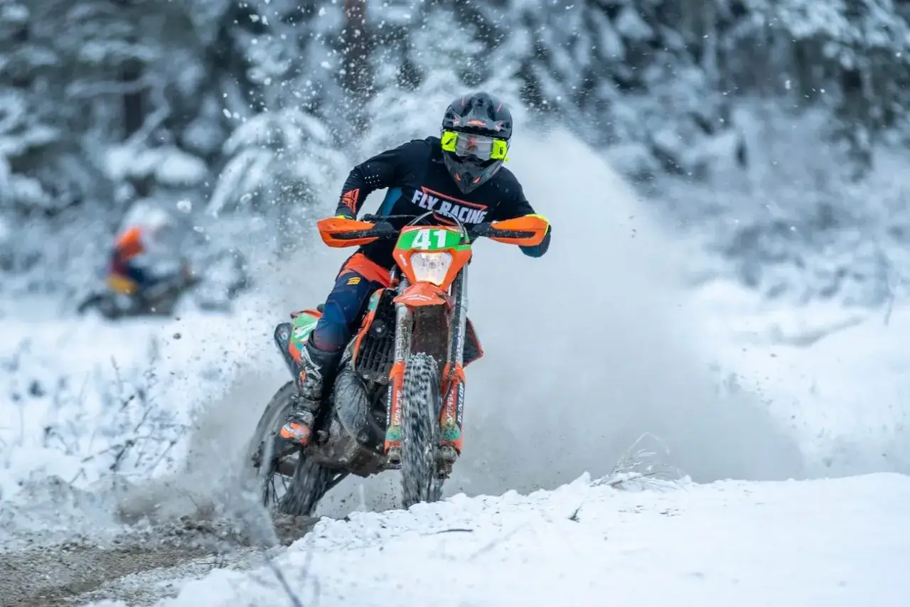 Motocyklista w akcji podczas wyścigu enduro w zimowej scenerii. To właśnie jest **enduro co to** za sport!