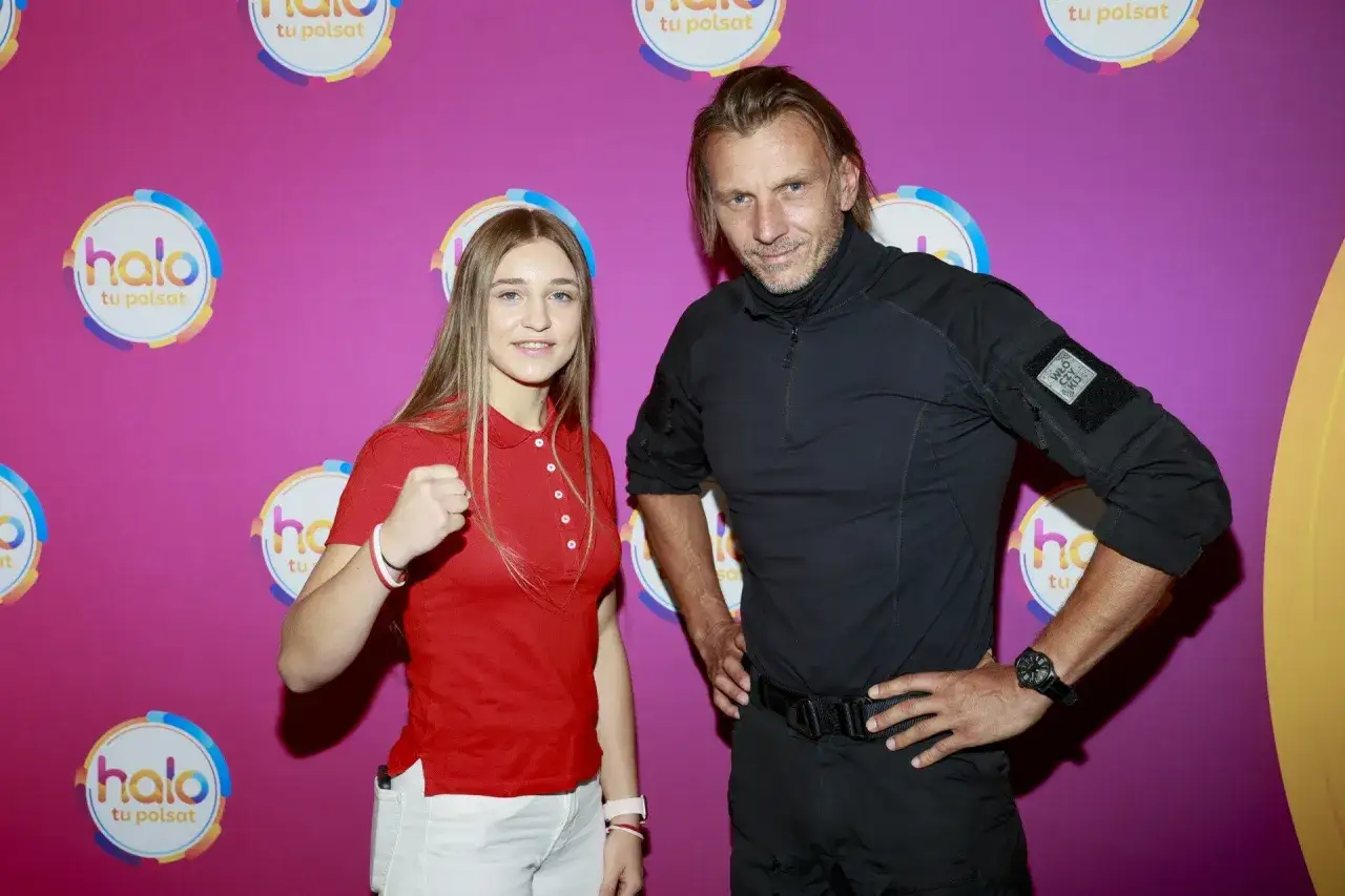 Julia Szeremeta, która pochodzi z Polski, pozuje z mężczyzną na tle różowej ścianki z logo "halo tu polsat".