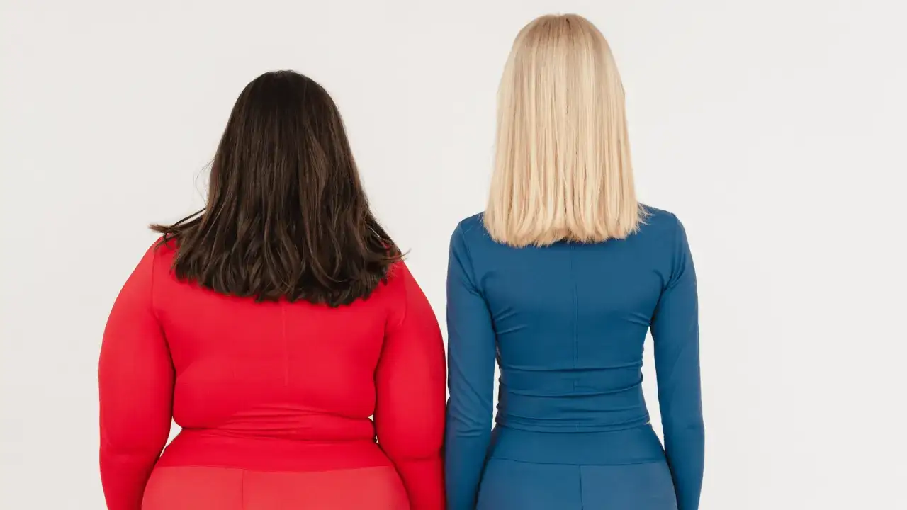 Dwie kobiety stojące tyłem, jedna w czerwonym, druga w niebieskim stroju.