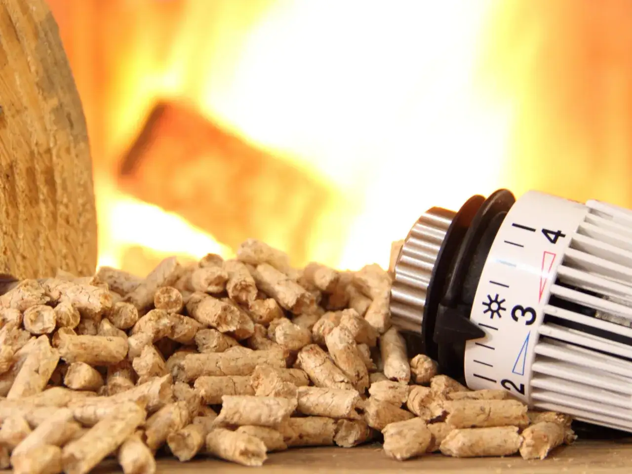 Stos drewna i termostat obok pelletu. Zastanawiasz się, ile ton pelletu na rok wystarczy do ogrzania domu?