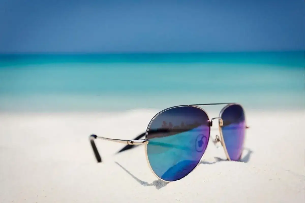 Okulary przeciwsłoneczne na plaży. Polaryzacja w okularach chroni przed odblaskami od wody, zapewniając czysty widok.