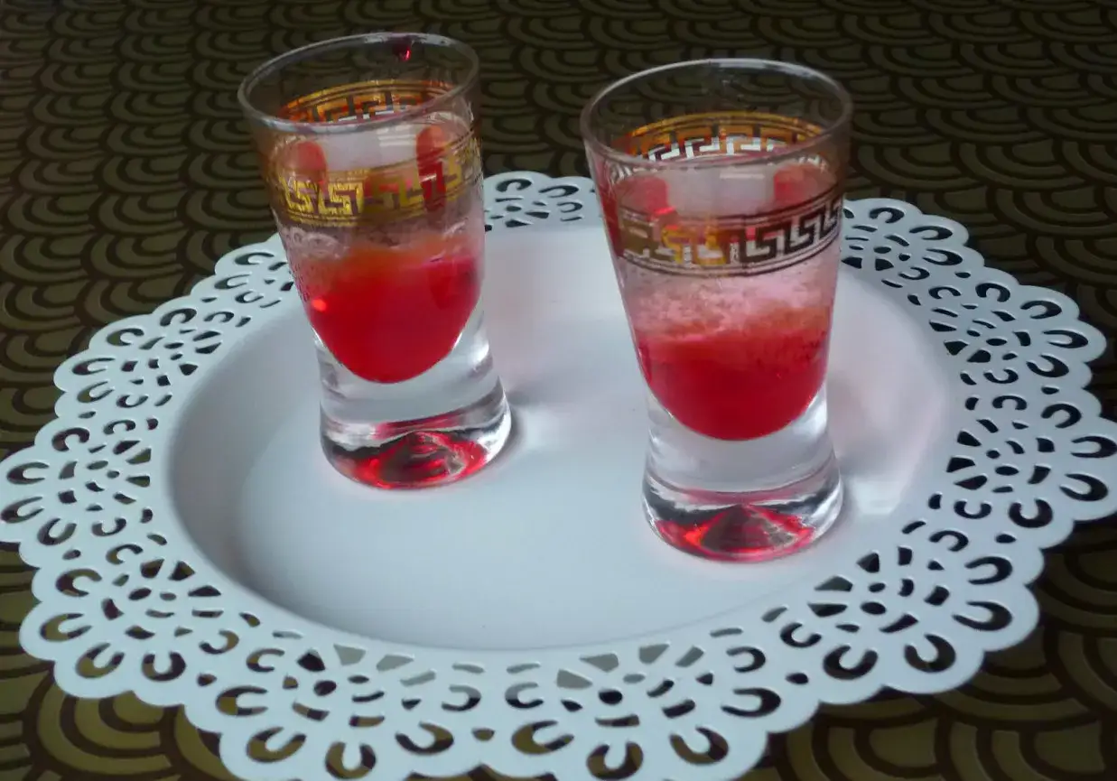 Dwa kieliszki z czerwonym drinkiem, ozdobione złotym wzorem. Wyglądają jakby miały moc, niczym wściekły pies drink.