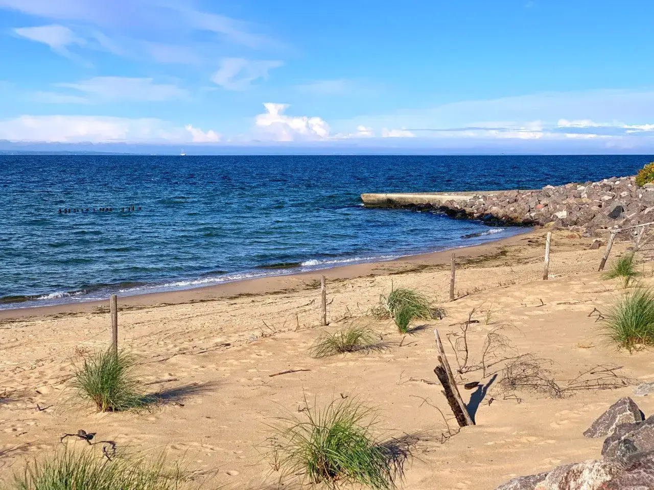 Plaża na półwyspie Św. Wawrzyńca z kamiennym falochronem i błękitnym morzem.