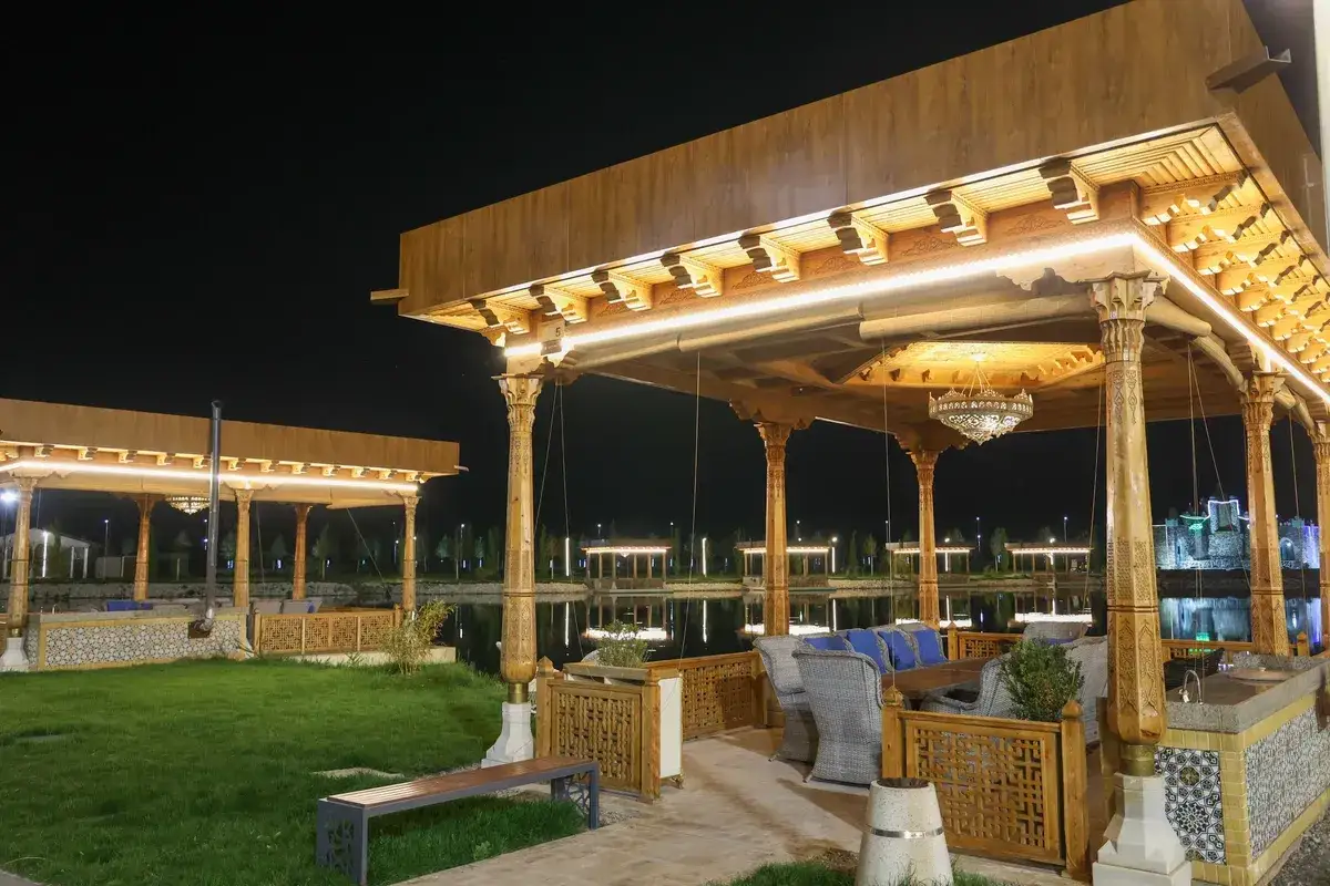 Drewniane ażurowe ścianki altany, ozdobione misternymi wzorami, tworzą przytulną przestrzeń.