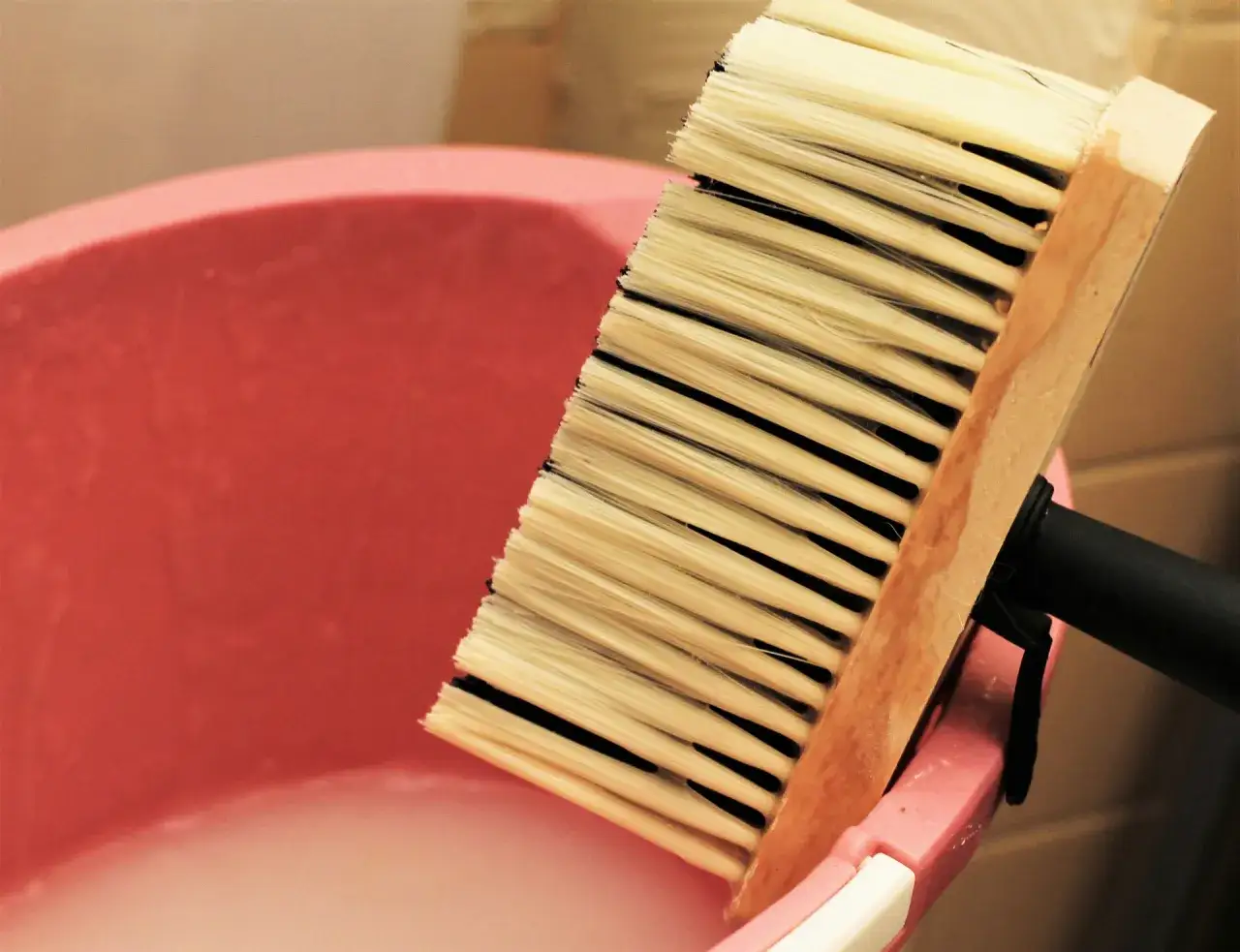 Pędzel do tapet nad różową miską z klejem. Zastanawiasz się, jak długo może stać rozrobiony klej do tapet?